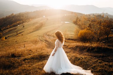 Güzel gelin bir dağ çayırında yürüyor