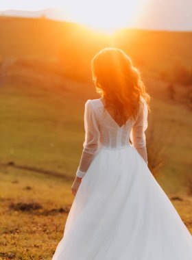 Tepe çayırında duran harika gelin sonbahar günbatımının tadını çıkarıyor. Bir dağ tepesi. İnanılmaz manzara..