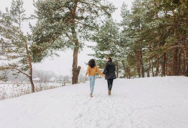Noel tatil birlikte karlı kış ormanda yürüyüş mutlu sevgi dolu çift harcama. Mevsimlik açık hava etkinlikleri.