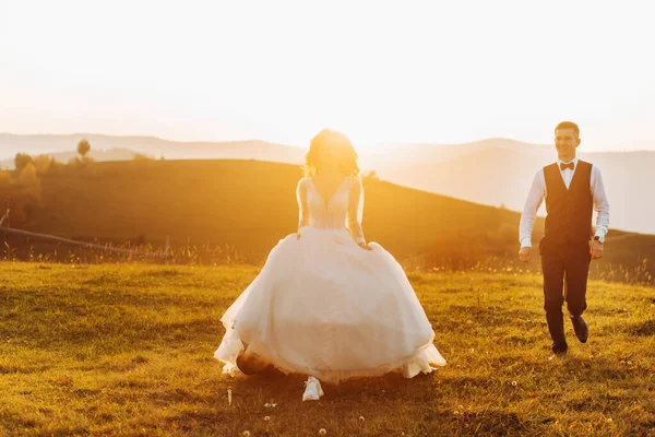 Recién Casados Enamorados Corren Una Colina Atardecer —  Fotos de Stock