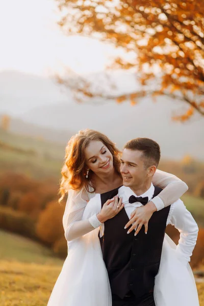 Sposo Lusso Porta Sua Sposa Sulle Spalle Sulle Colline Tramonto — Foto Stock