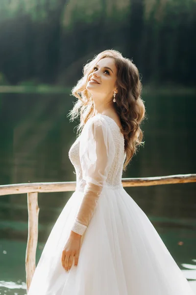 Lüks bir gelinlik içinde güzel bir gelin dağ gölü manzarasının keyfini çıkarıyor.