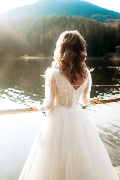 Cute bride in luxury wedding dress near the lake. Wedding in mountains