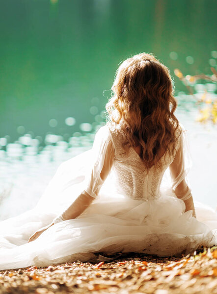The young bride sitting near the lake
