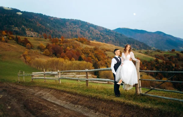 Novomanželé Lásce Stojí Dřevěného Plotu Pozadí Podzimních Hor — Stock fotografie