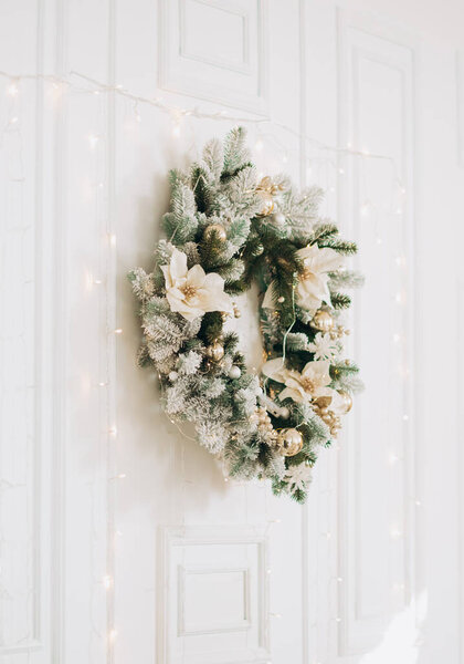 A traditional bright Christmas wreath hanging on a white wall. Christmas concept, new year.