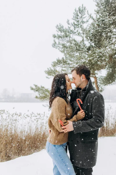 Karlı bir parkta ellerinde lolipoplarla poz veren sevimli bir çift..