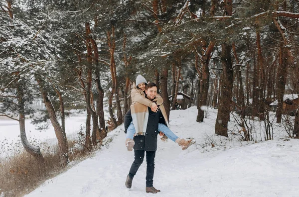 Bir Adam Karlı Bir Ormanda Yürürken Kız Arkadaşını Sırtında Taşıyor — Stok fotoğraf