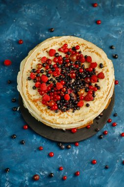 Mavi arka planda böğürtlenli krep. Kahvaltıda. Tatlı ev yapımı krep yığını