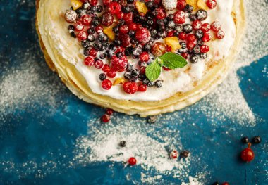 Turkuaz arka planda pudra şekerli krep yığını. Metin için alanı kopyala.