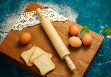 Yuvarlak iğne, un, yumurta, ahşap arka planda ekmek, üst manzara..