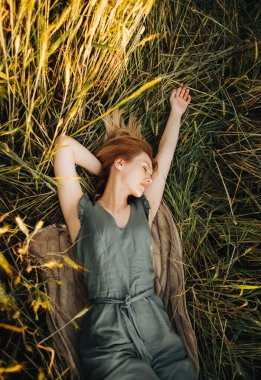 Yeşil takım elbiseli rüya sarışının gözleri buğday tarlasında kulaklarının arasında kapalı yatıyor.