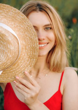 Şirin kız yüzünün bir kısmını hasır şapkayla kapatıyor..