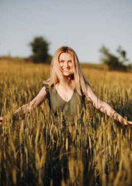 Gün batımında buğday tarlasında güzel sarışın kız