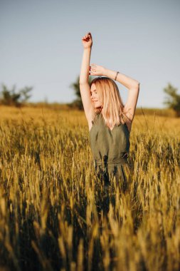 Buğday tarlasında elleri havada poz veren şık takım elbiseli hoş bir kız.