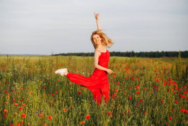 Kırmızı elbiseli zarif sarışın haşhaş tarlasına atlıyor.