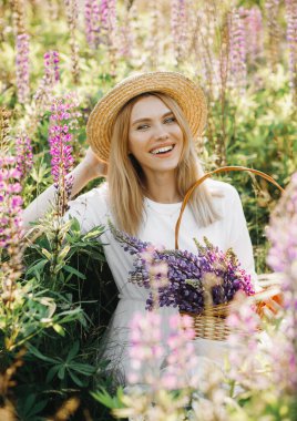 Beyaz elbiseli, kısa saçlı genç bir sarışın. Kadın lup tarlasında poz veriyor.