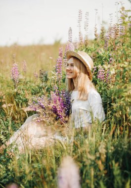 Beyaz elbiseli, kısa saçlı genç bir sarışın. Kadın lup tarlasında poz veriyor.