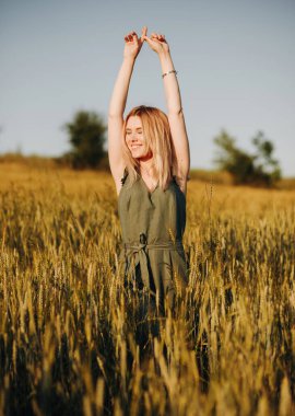 Buğday tarlasında elleri havada poz veren şık takım elbiseli hoş bir kız.