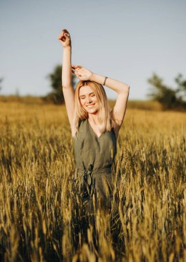 Buğday tarlasında elleri havada poz veren şık takım elbiseli hoş bir kız.