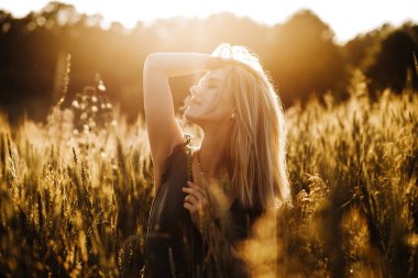 Güzel bir sarışının portresi Gün batımında buğdayın tadını çıkarıyor.