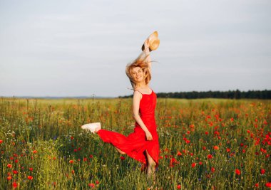 Kırmızı elbiseli zarif sarışın haşhaş tarlasına atlıyor.