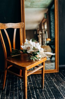 Gelinin buketi aynanın yanındaki sandalyede. Gelinin sabahı