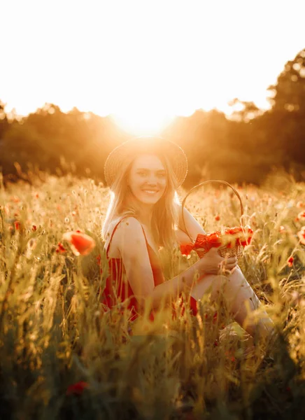 Hasır şapkalı çekici kız elinde haşhaş sepetiyle haşhaş tarlasında poz veriyor.