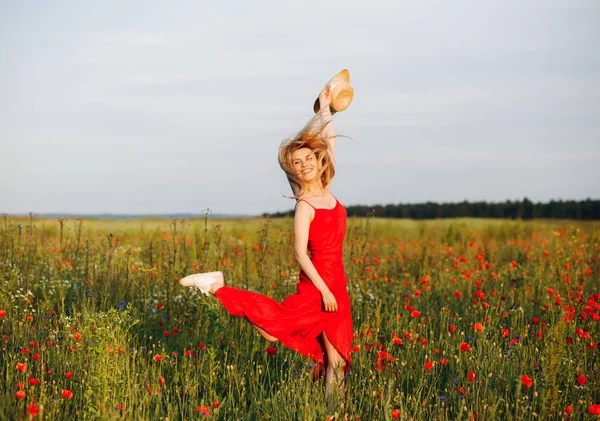 Kırmızı elbiseli zarif sarışın haşhaş tarlasına atlıyor.