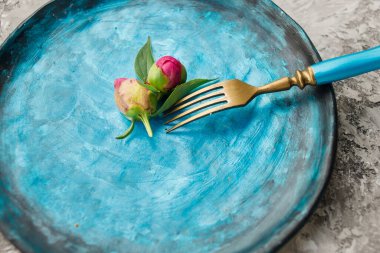 Renkli mutfak seti, gri arka planda şakayık çiçekleri ve çatallı mavi tabak..