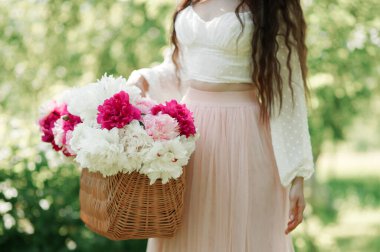 Elinde sepet dolusu taze şakayık tutan bir kadın. Bir buket pembe ve beyaz çiçek. Yaz duvar kağıdı.