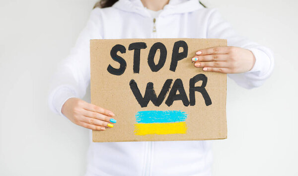Rashist war against Ukraine. Woman with a message to stop the war. "STOP WAR" text plate.