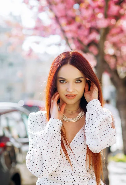 春の桜を背景にした若い赤髪の女性の肖像 — ストック写真