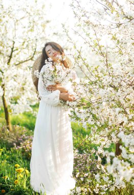 Güzel bir kızın bahar portresi harika bir elbiseyle güneşli bir günde baharın tadını çıkarıyor..