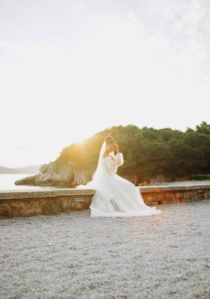 Όμορφη Νύφη Λευκό Φόρεμα Που Ποζάρει Καθισμένη Στην Παραλία Ηλιοβασίλεμα — Φωτογραφία Αρχείου