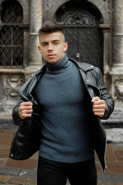 Modern genç çocuk siyah bir kapının yanında poz veriyor.