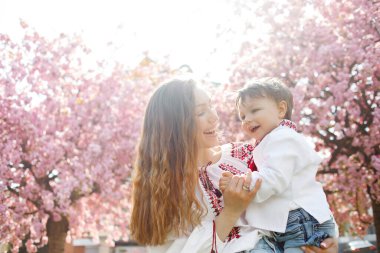 Çiçek açan bahar bahçesinde mutlu bir kadın ve çocuk. Anneler Günü Tatil Konsepti