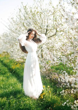 Güzel bir kızın bahar portresi harika bir elbiseyle güneşli bir günde baharın tadını çıkarıyor..