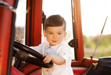 Gün batımında traktörde oturan küçük çocuk.