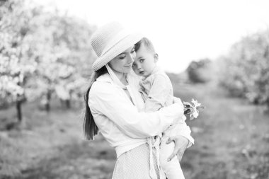 Mutlu anne ve bebeğinin portresi. Anne ve oğlunun güzel dokunaklı sahnesi. Baharda çiçek açan bahçe.
