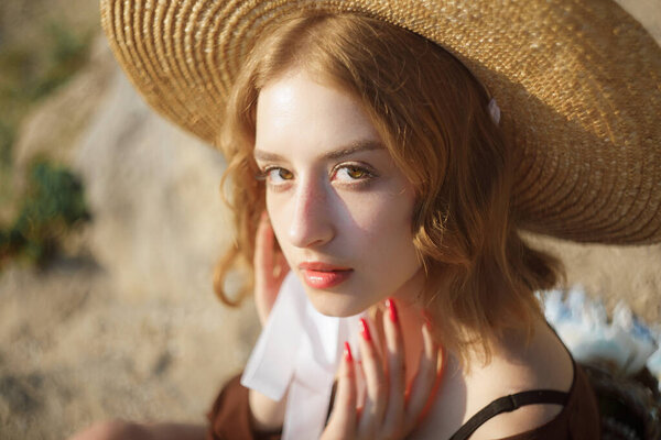 Portrait of sweet blonde girl in straw hat posing on a background of the city.