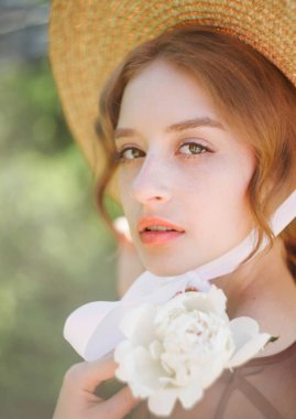 Güneş batarken hasır şapkalı şirin bir sarışının yakın plan portresi. Klasik ton