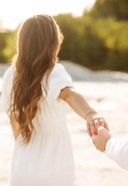 A man holds the hand of his future wife. The girl shows a wedding ring on her hand.
