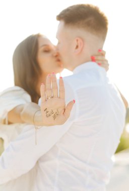 Romantic portrait of a young couple. Just got engaged. Shallow depth of field with focus on the diamond ring and inscription on the palms. Smiling and happy