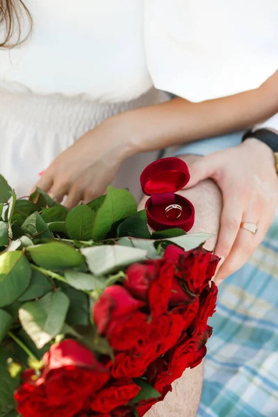 Marriage proposal. Red box with a ring and roses on the background of the couple.