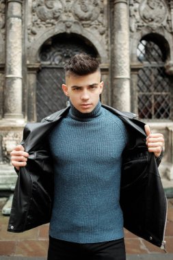 Modern genç çocuk siyah bir kapının yanında poz veriyor.