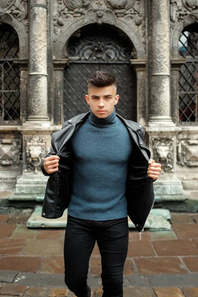 Modern genç çocuk siyah bir kapının yanında poz veriyor.