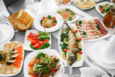 Fish dishes on the banquet table, logos, snacks, vegetables
