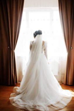 A lovely bride is posing in front of the window