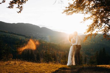Beautiful newlyweds walking in the mountains. Wedding in boho style.